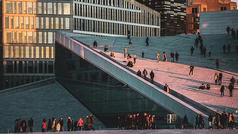 Mennesker som går på Operashuset i Oslo i solnedgang. Foran Barcode bygg. Illustrasjonsbilde for Vipps i Wordpress.